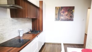 A modern kitchen with white cabinets, a wooden countertop, and a stainless steel range hood. - Apartament Ogarna II (Gdansk)