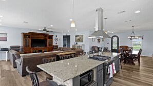 Un'ampia cucina con un'isola grande, mobili in legno e un'area pranzo con divano e sedie.