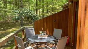 Eine Holzterrasse mit einem runden Tisch und vier Stühlen, umgeben von einer Holzgeländer.