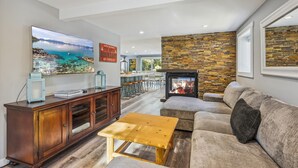 A living room with a stone wall, a fireplace, a sofa, and a TV.