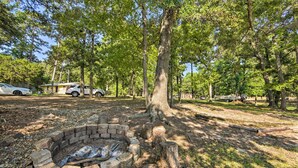 Een camping met een vuurplaats, bomen en campers.