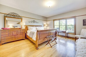 A bedroom with a wooden bed, a dresser, a chair, and a large window. - Hot Tub! Mtn-View Family Haven in Black Forest (Colorado Springs)