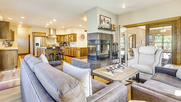 Una sala de estar moderna con chimenea, una cocina al fondo y un comedor con una mesa y sillas blancas.
