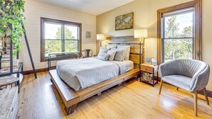 Un dormitorio con una cama de madera, dos lámparas de noche, una silla y una ventana con vistas.