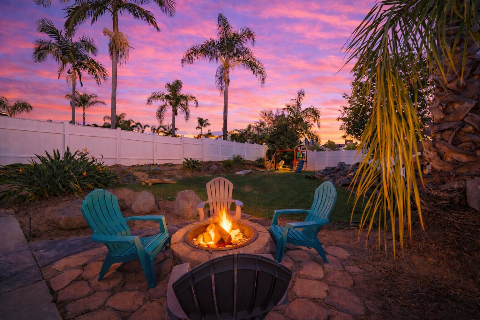 An outdoor seating area with a fire pit and Adirondack chairs.