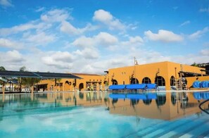 Relax by the resort pool surrounded by a beautiful building with multiple arches.