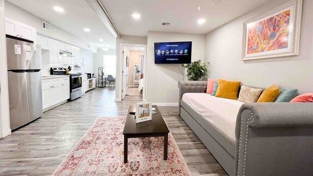 Una sala de estar moderna con un sofá gris, una mesa de centro y un televisor de pantalla plana mostrando una pantalla de bienvenida.