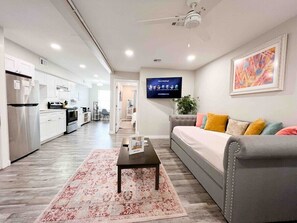 A modern living room with a grey sofa, a coffee table, and a flat-screen TV displaying a welcome screen. - Central+RemoteWork+Ext Stay Discts+Min2Beach (Corpus Christi)