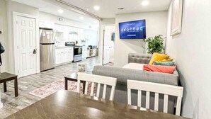 Una sala de estar moderna con una mesa de comedor, sofá y televisor.
