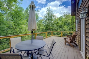 A wooden deck with a round table and chairs, surrounded by a wooden railing. - Cozy Boone Cabin w/ Deck: Close to Downtown! (Boone)