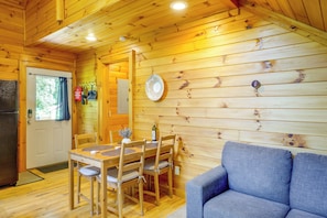 Ein Holzinterieur mit einem Esstisch, Stühlen, einem Sofa und einer Tür mit Fenster.