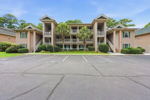 A multi-story hotel with a central courtyard, balconies, and a parking lot.