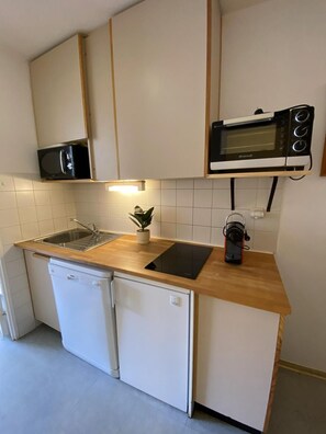 Una cocina compacta con lavavajillas, microondas y horno empotrado.