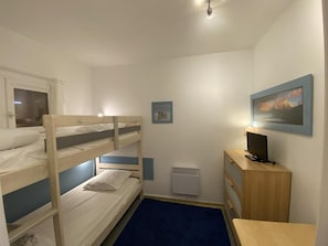 A bunk bed room with a desk, a heater, and a picture on the wall.