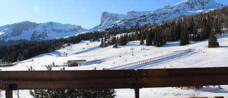 Une piste de ski enneigée, avec une clôture en bois au premier plan.
