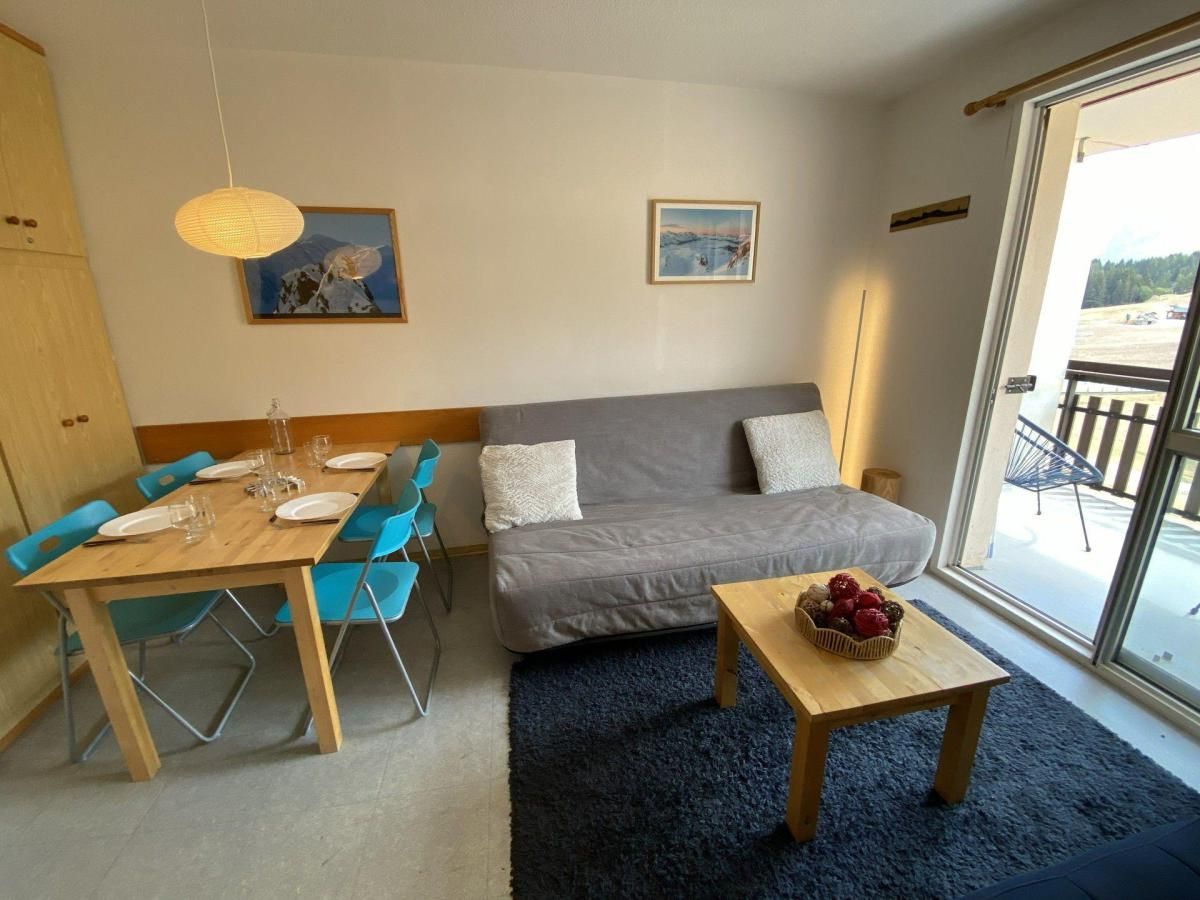 Une pièce avec une table  à manger dressée pour quatre personnes, un canapé gris et une petite table sur laquelle se trouvent des fruits.