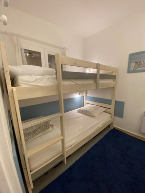 Habitación con literas, ventana, un cuadro en la pared y alfombra azul.