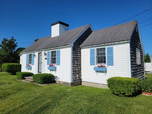 A two-story house with a gabled roof, white siding, and blue shutters.