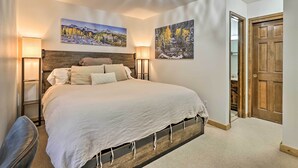 A bedroom with a large bed, two wall-mounted lamps, and two paintings depicting nature scenes. - Walk to Ski Lift: Breckenridge Retreat w/ 2 Decks! (Breckenridge)