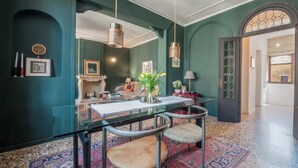 Un coin repas avec une table en verre, deux chaises, un vase de fleurs et un tapis à motifs.
