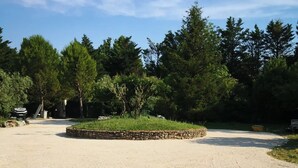 Uma área de estacionamento com calçamento de cascalho, borda de pedra e um trecho de grama no centro.