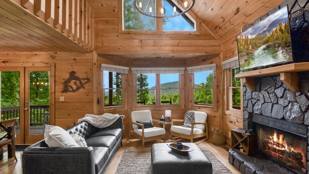 A cozy cabin interior with a fireplace, wooden furniture, and large windows offering scenic views. - *NEW* Modern Rustic Cabin w/ AMAZING views! Hot Tub, 2 King Suites, Pet Friendly (Morganton)