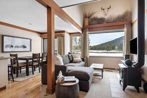 Una sala moderna con un sofá seccional, un comedor con mesa y sillas de madera, una chimenea y un ventanal con vistas al exterior.