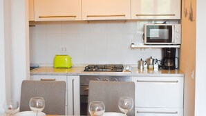 A modern kitchen with white cabinets, a microwave, a gas stove, and a bright yellow toaster. - New Bright and Quiet in the Heart of Trastevere (Roma)