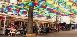 A street with outdoor seating and umbrellas. - ON THE BANKS OF SEINE-AN EXPLICIT 17TH CENT.TOWNHOUSE LE MARAIS VILLAGE ST PAUL (Paris)