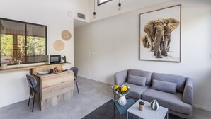 A modern living room with a grey sofa, a wooden desk, and a large elephant artwork on the wall. - Houat - Appartement 2p avec balcon à Rennes (Rennes)