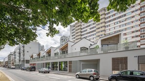 A modern urban street with multi-story residential buildings, parked cars, and a sidewalk. - Houat - Appartement 2p avec balcon à Rennes (Rennes)
