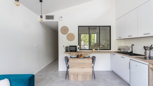 A modern kitchen with a dining area, white cabinets, and a blue sofa. - Moines - Appartement moderne et confortable (Rennes)