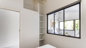 A minimalist bedroom with a large window, a bed, and a built-in shelving unit. - Molène - Cosy, à quelques minutes du centre-ville (Rennes)