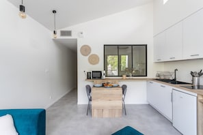 Eine moderne Küche mit Essbereich, weißen Schränken und einem blauen Sofa.