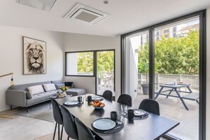 Ein moderner Essbereich mit einem langen Tisch, Stühlen und einem grauen Sofa.