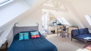 A bedroom with a bed, a desk, and a chair in a loft-style room with skylights. - Teranga - Studio avec grande terrasse dans Rennes (Rennes)