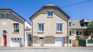 A two-story residential building with a beige facade, a red door, and a stone base. - Teranga - Studio avec grande terrasse dans Rennes (Rennes)