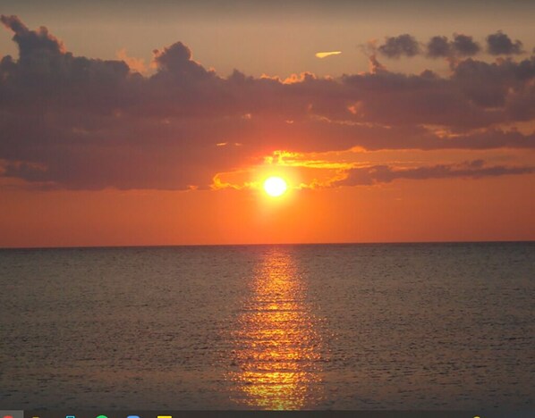 A sunset over a calm sea with a visible horizon line.