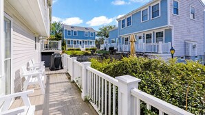 A residential area with a wooden deck, white railings, and houses with blue and white siding. - Luxury 2-Story PTown Condo: 5 Min Walk to Commercial St. Private Patio & Parking (Provincetown)