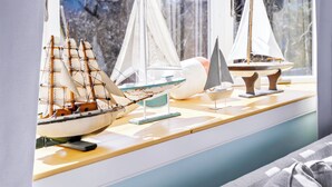 A room with a large window displaying model sailboats. - Luxury 2-Story PTown Condo: 5 Min Walk to Commercial St. Private Patio & Parking (Provincetown)