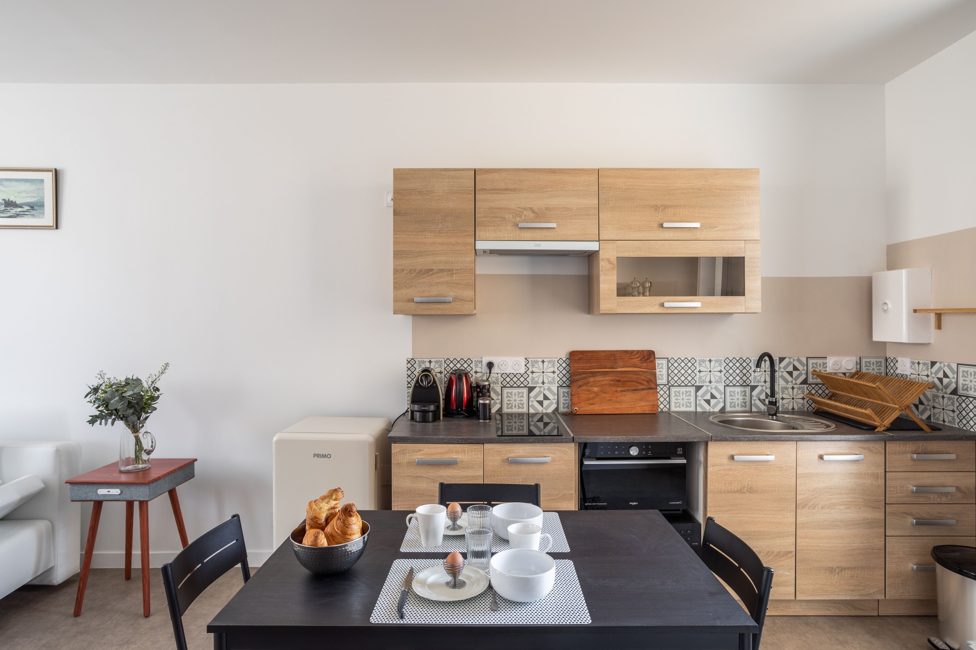 Eine moderne Küche mit Holzschränken, einer eingebauten Mikrowelle und einem Spülbecken.