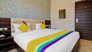 A hotel room with a bed, a nightstand, a wall with geometric patterns, and a door. - Itsy Hotels Jashan (Mohali)