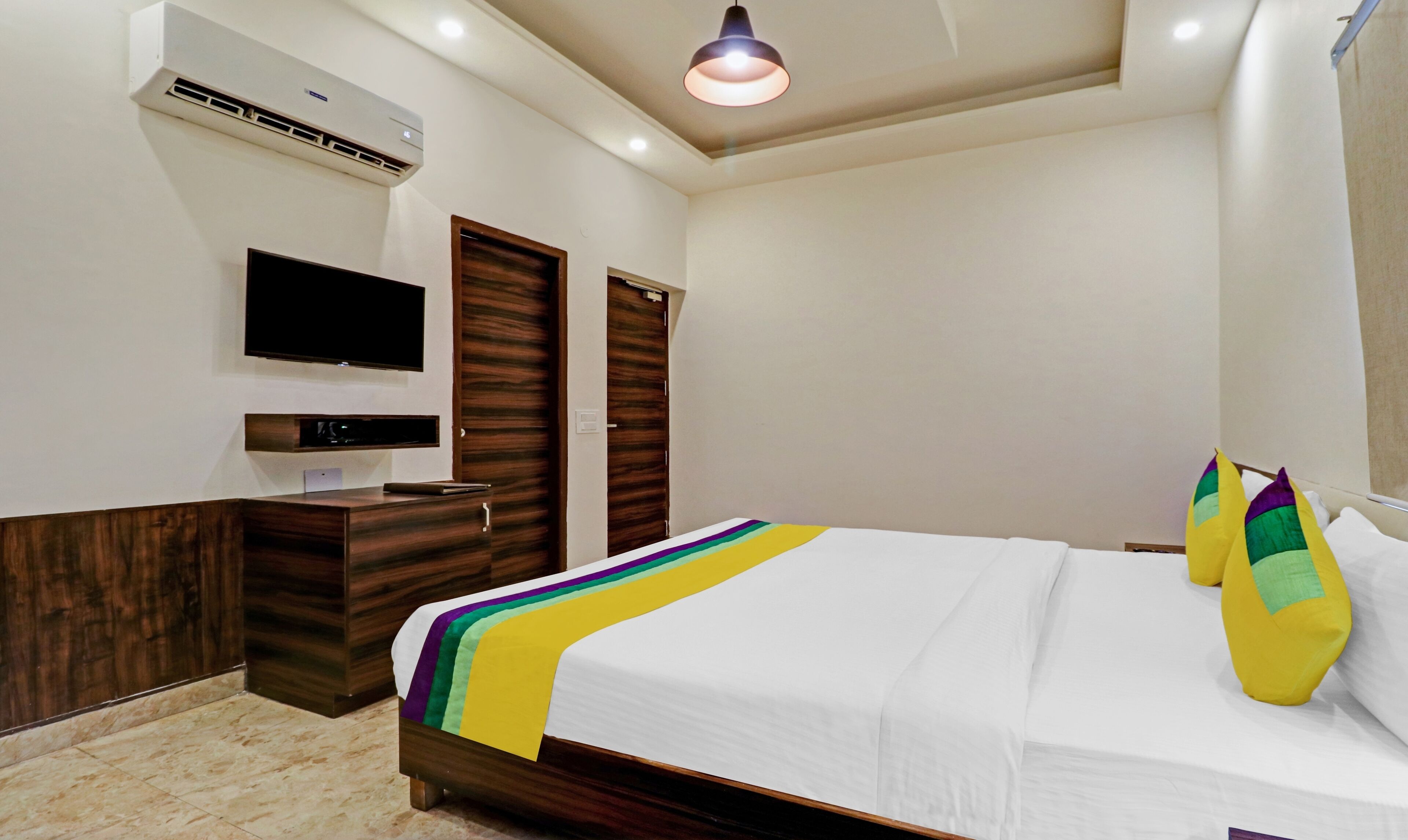 Habitación de hotel con cama, televisión fijada a la pared, armario y aire acondicionado.