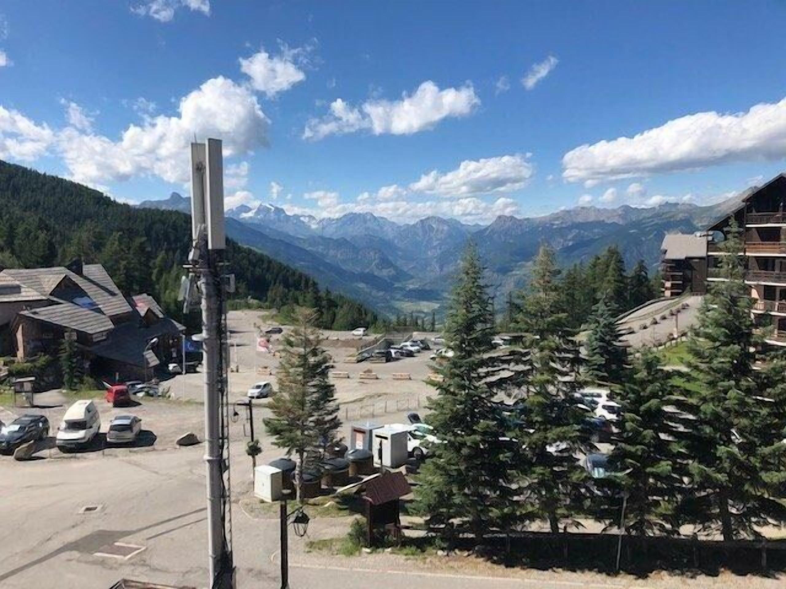 A mountain resort with a parking area, buildings, and a view of the mountains.