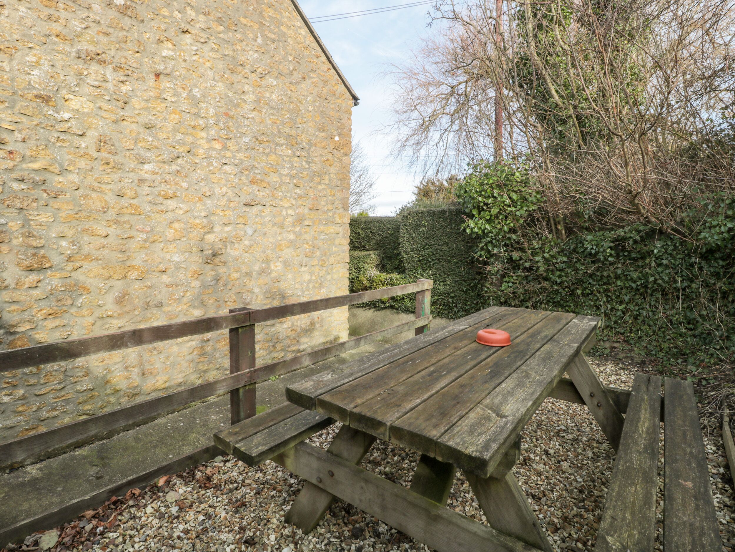 A stone building with a wooden picnic table and benches.