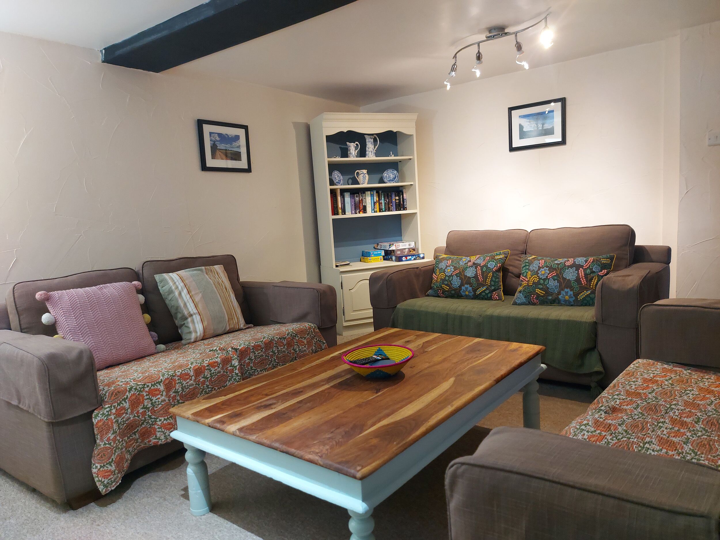 A cozy living room with two sofas, a wooden coffee table, and a bookshelf.