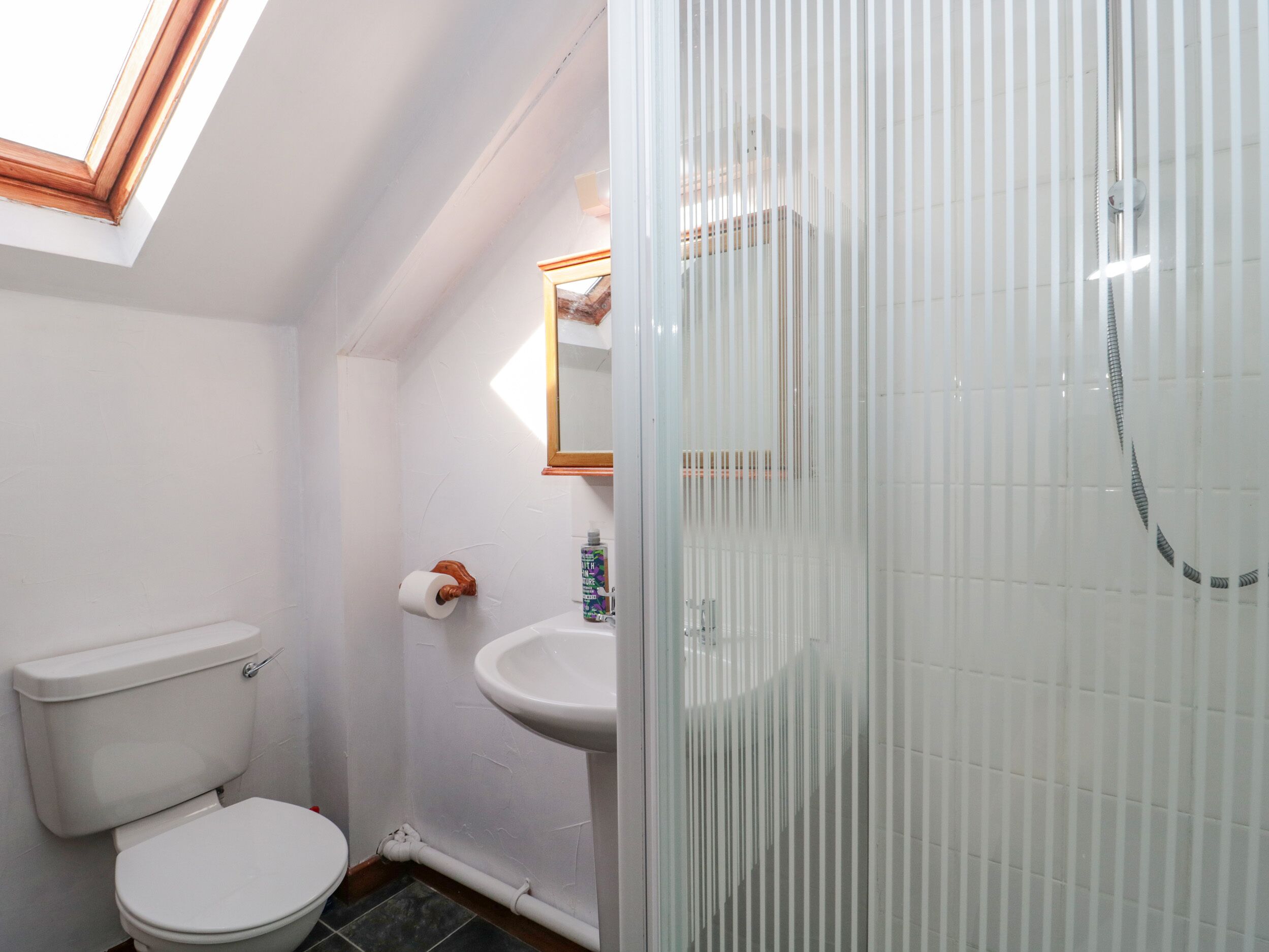 A bathroom with a toilet, sink, and shower.