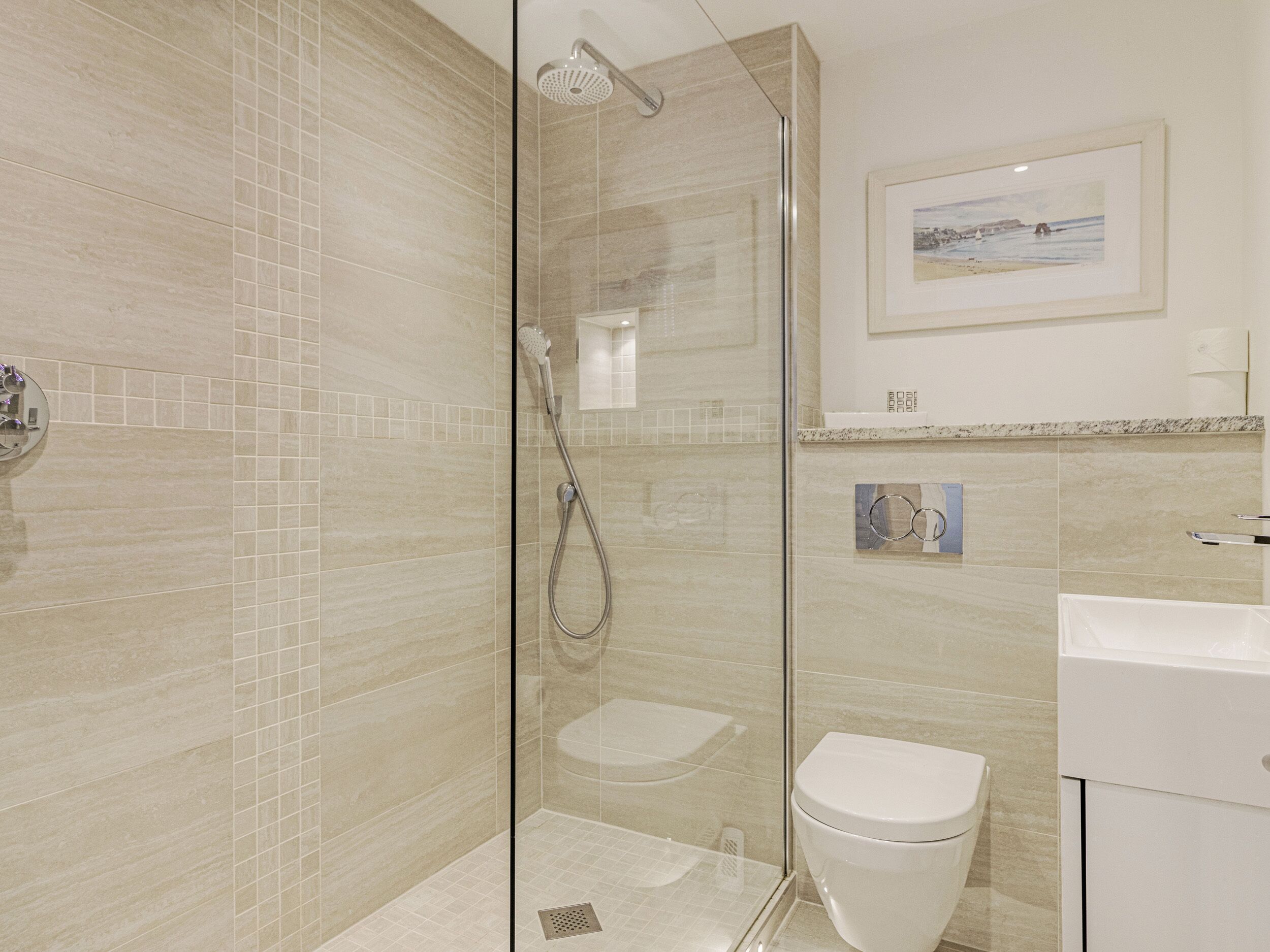 Une salle de bain moderne dotée d’une douche à parois de verre, de toilettes et d’un lavabo.