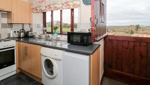 A modern kitchen with a washing machine, a microwave, and a sink. - The Sty (Bridport)