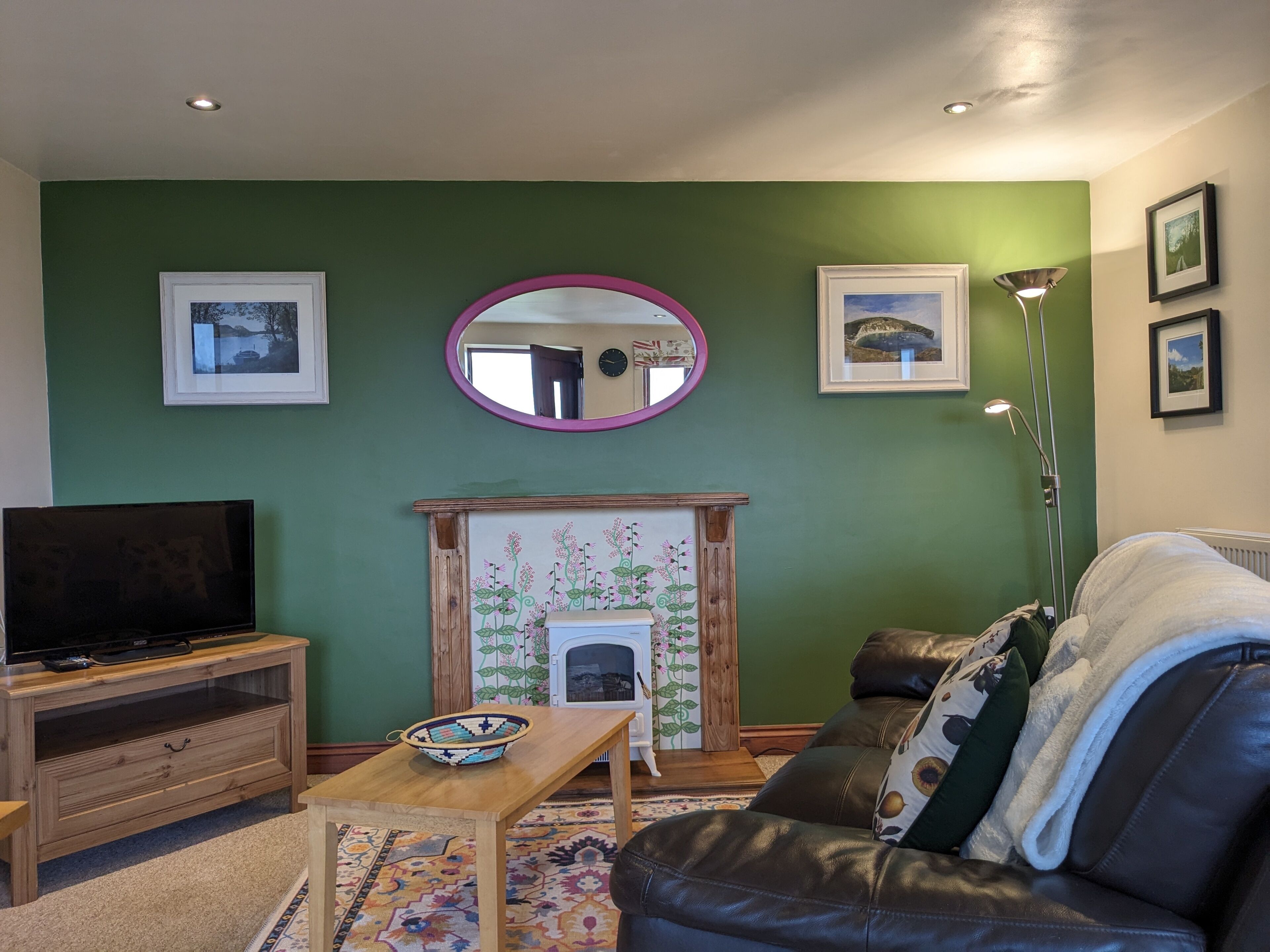 A living room with a television, sofa, coffee table, and fireplace.